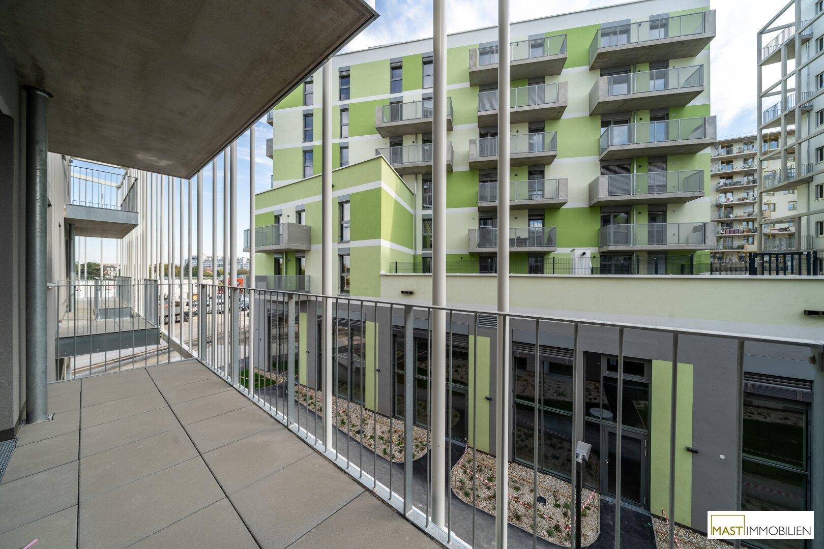 Balkon mit Weitblick auf die moderne Wohnanlage mit ihren charakteristischen grünen Fassaden.