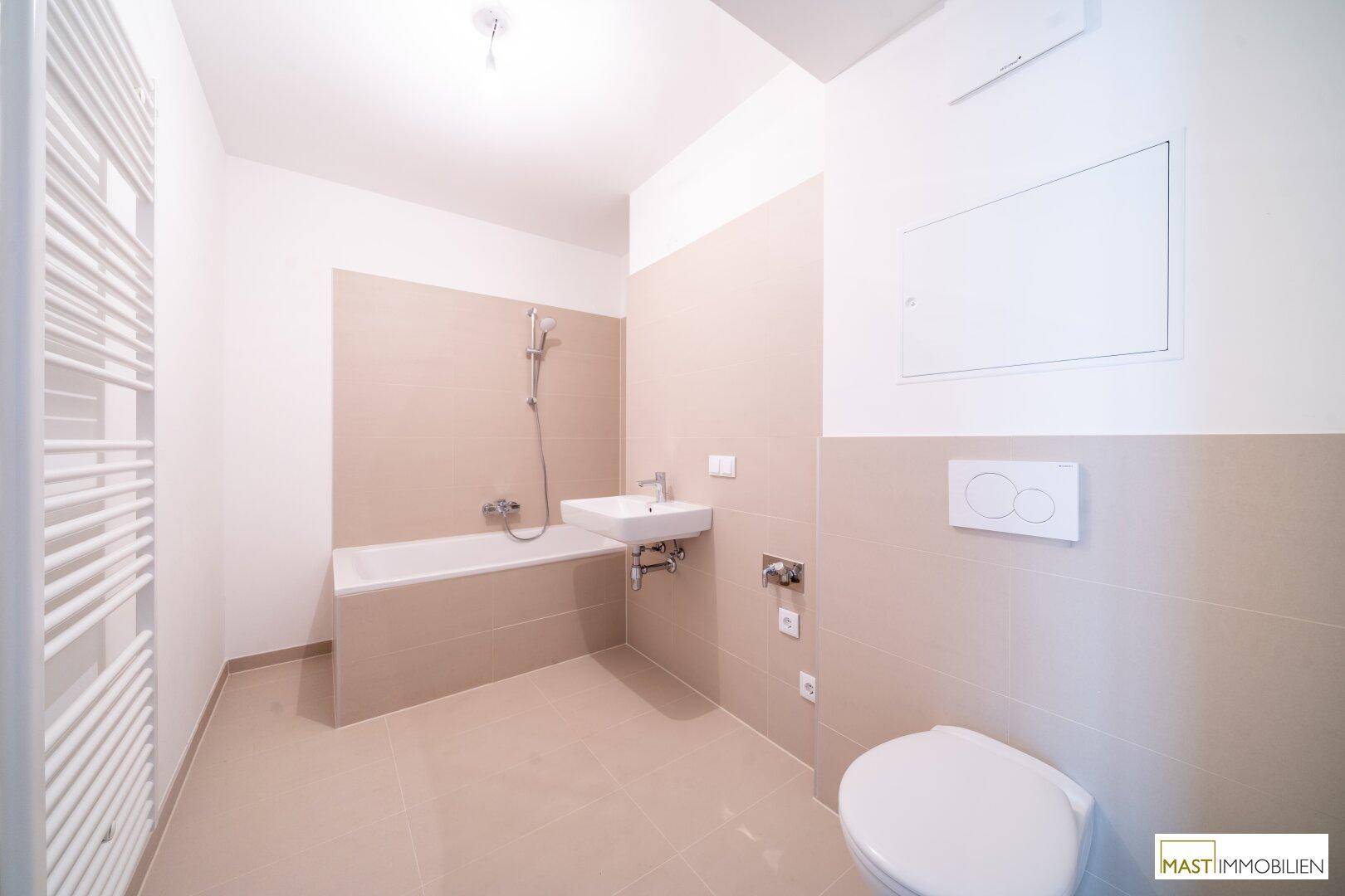 Modernes Badezimmer mit Badewanne, Dusche, Wand-WC, Einzelwaschbecken und beheiztem Handtuchhalter.