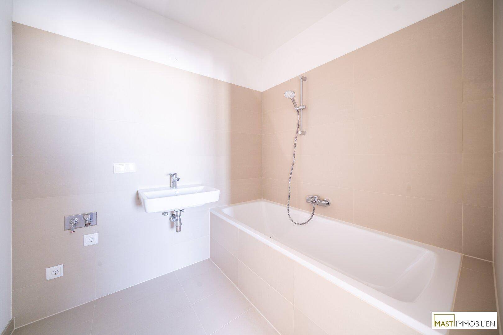 Modernes Badezimmer mit Badewanne, Einzelwaschbecken und beigefarbenen Fliesen an Wänden und Boden.