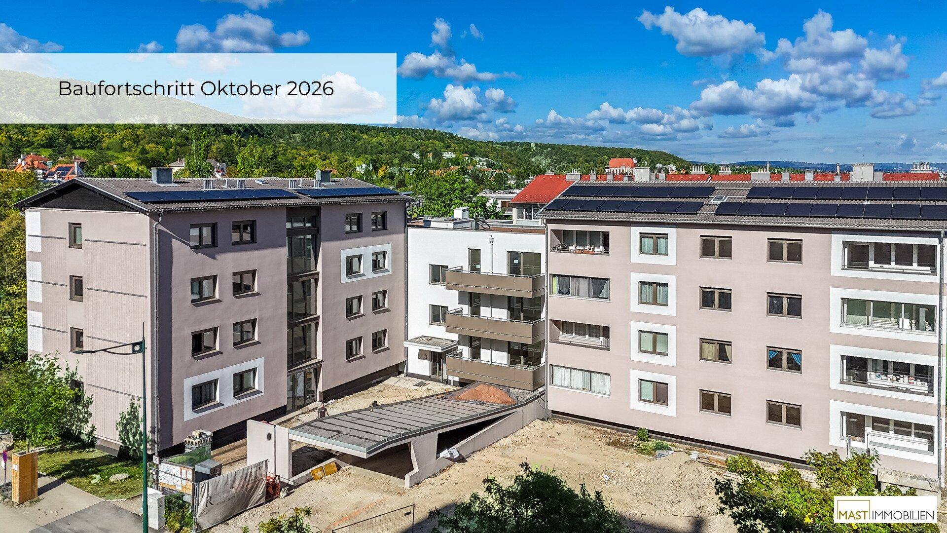 Luftaufnahme von zwei modernen Wohngebäuden mit Solaranlagen auf den Dächern und Baustellenbereich.