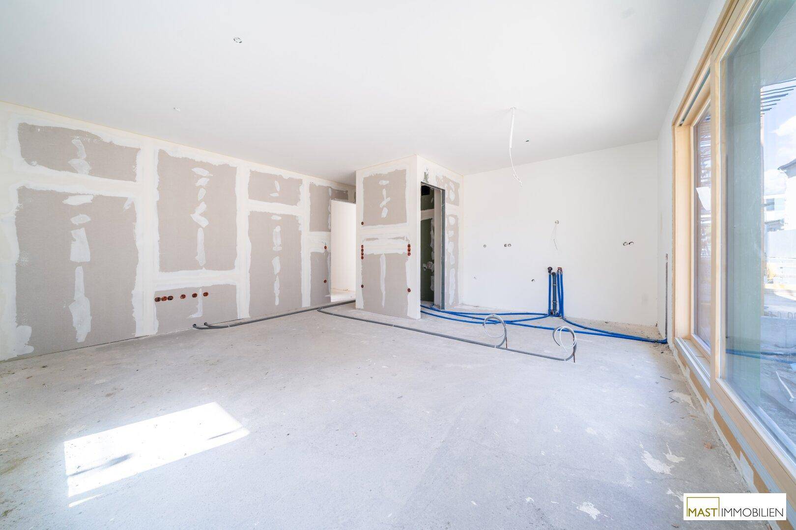 Innenraum im Rohbau mit vorbereiteten Wänden und Leitungen, bereit für die weitere Gestaltung und Fertigstellung.