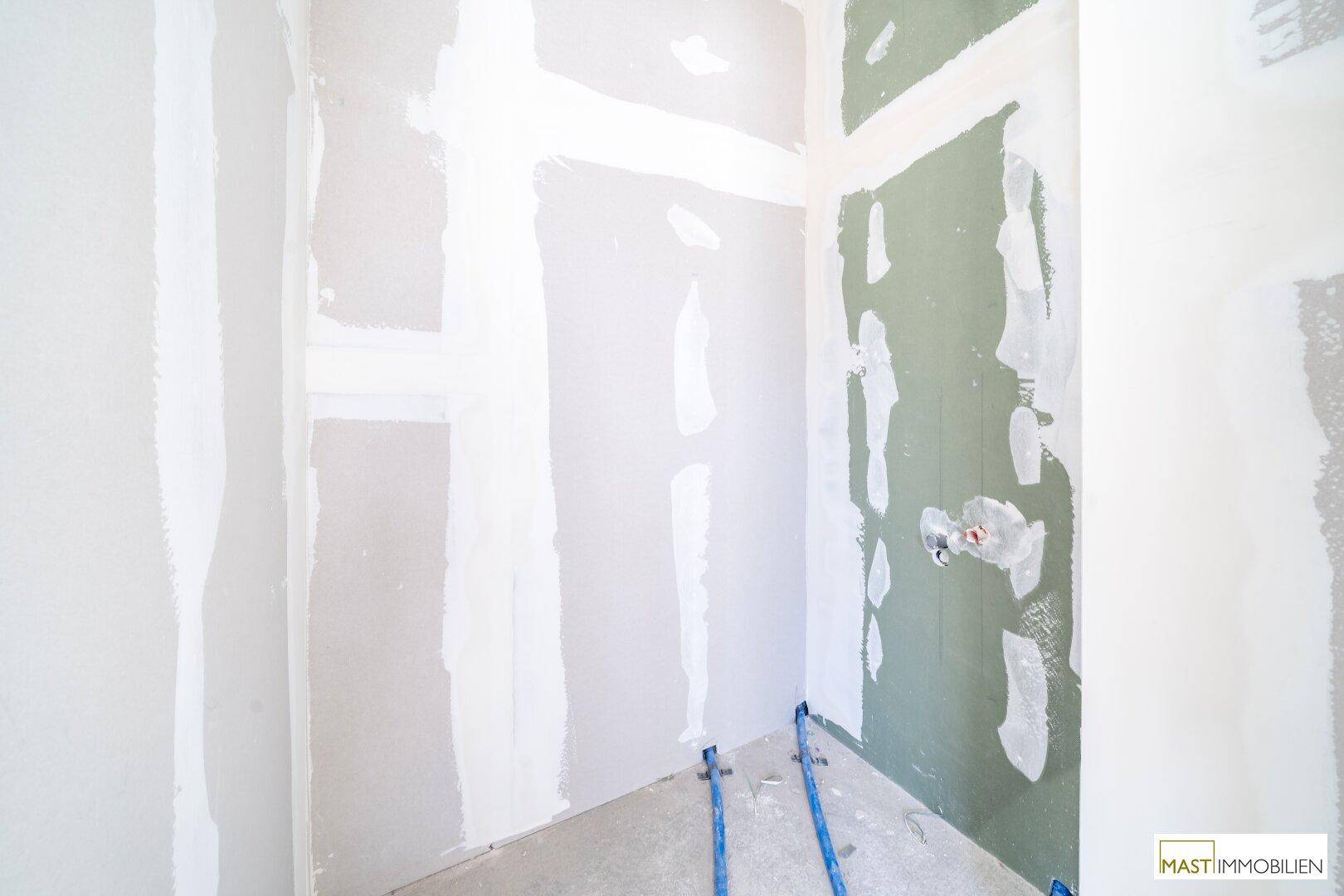 Unfertiges Badezimmer mit vorbereiteten Wänden und Anschlüssen für Sanitärinstallationen, bereit für den Ausbau.