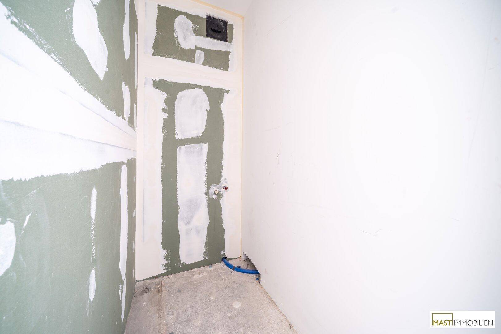 Unfertiger Innenraum mit Trockenbauwänden und vorbereiteten Installationen, wartet auf den weiteren Ausbau.