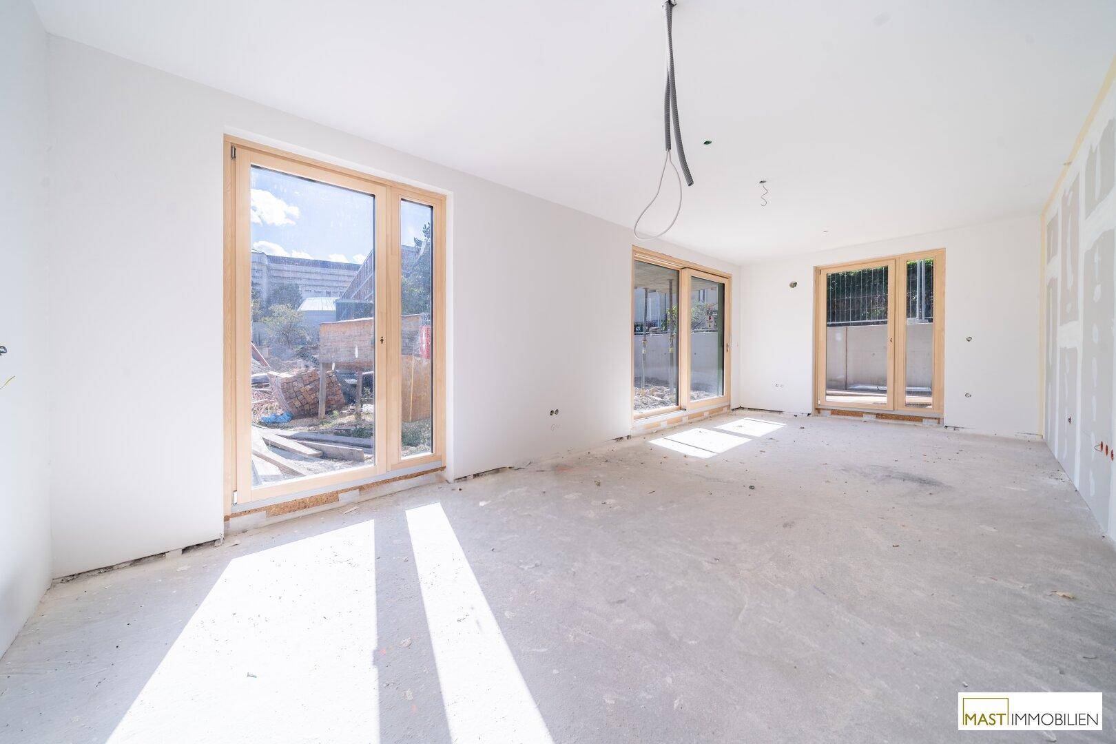 Heller Innenraum im Rohbau mit großen Fenstern und Blick ins Freie, bereit für den weiteren Ausbau.