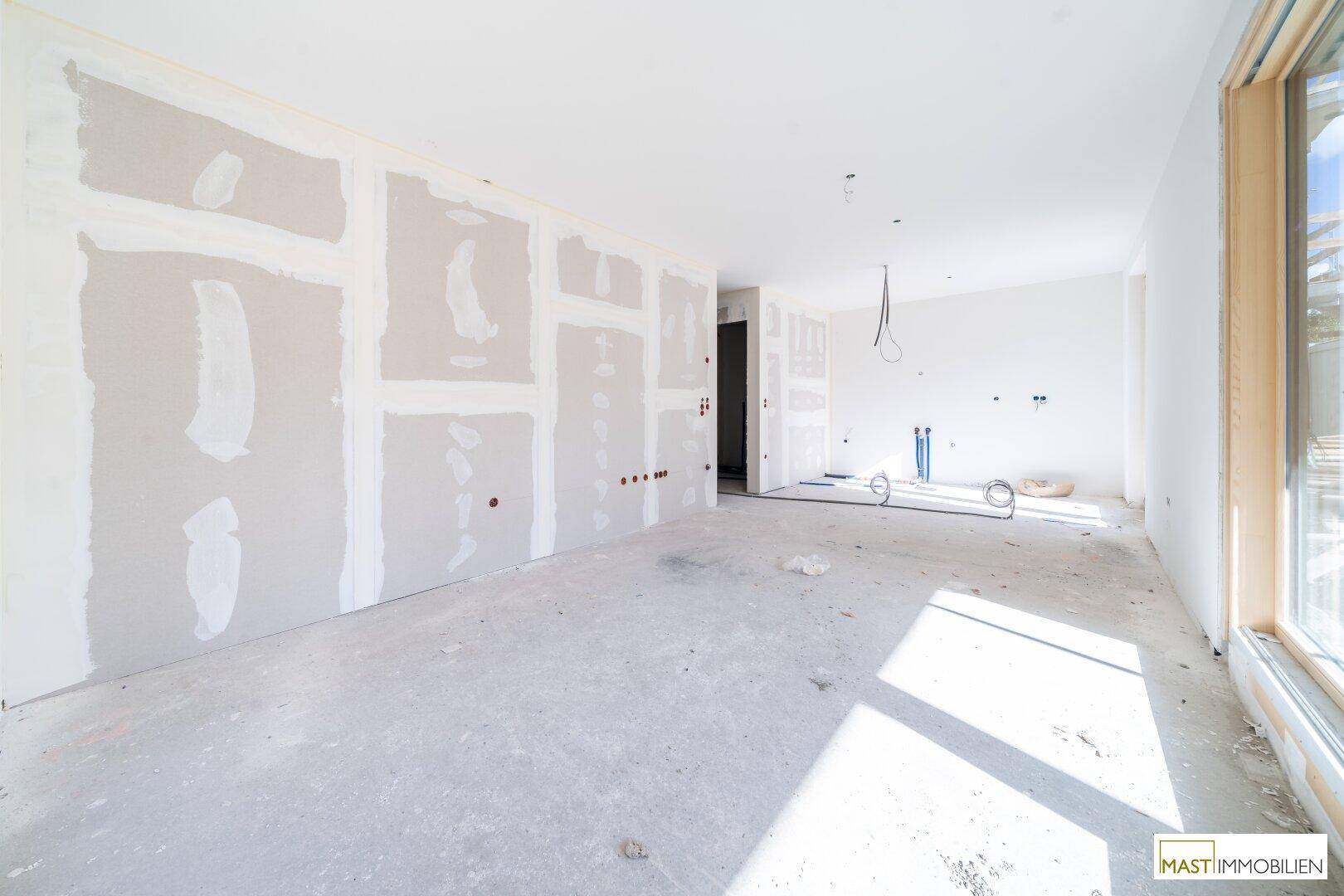 Rohbau eines Zimmers mit Trockenbauwänden und sichtbaren Installationen, wartet auf den Innenausbau.