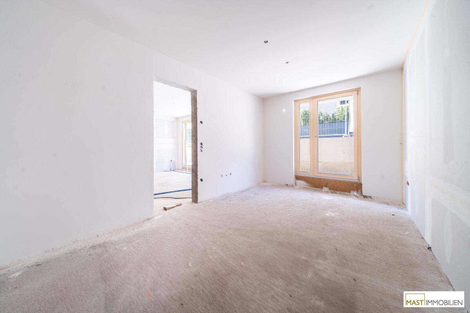 Heller Rohbau mit großen Fenstern und vorbereiteten Anschlüssen für den Innenausbau des Wohnbereichs.