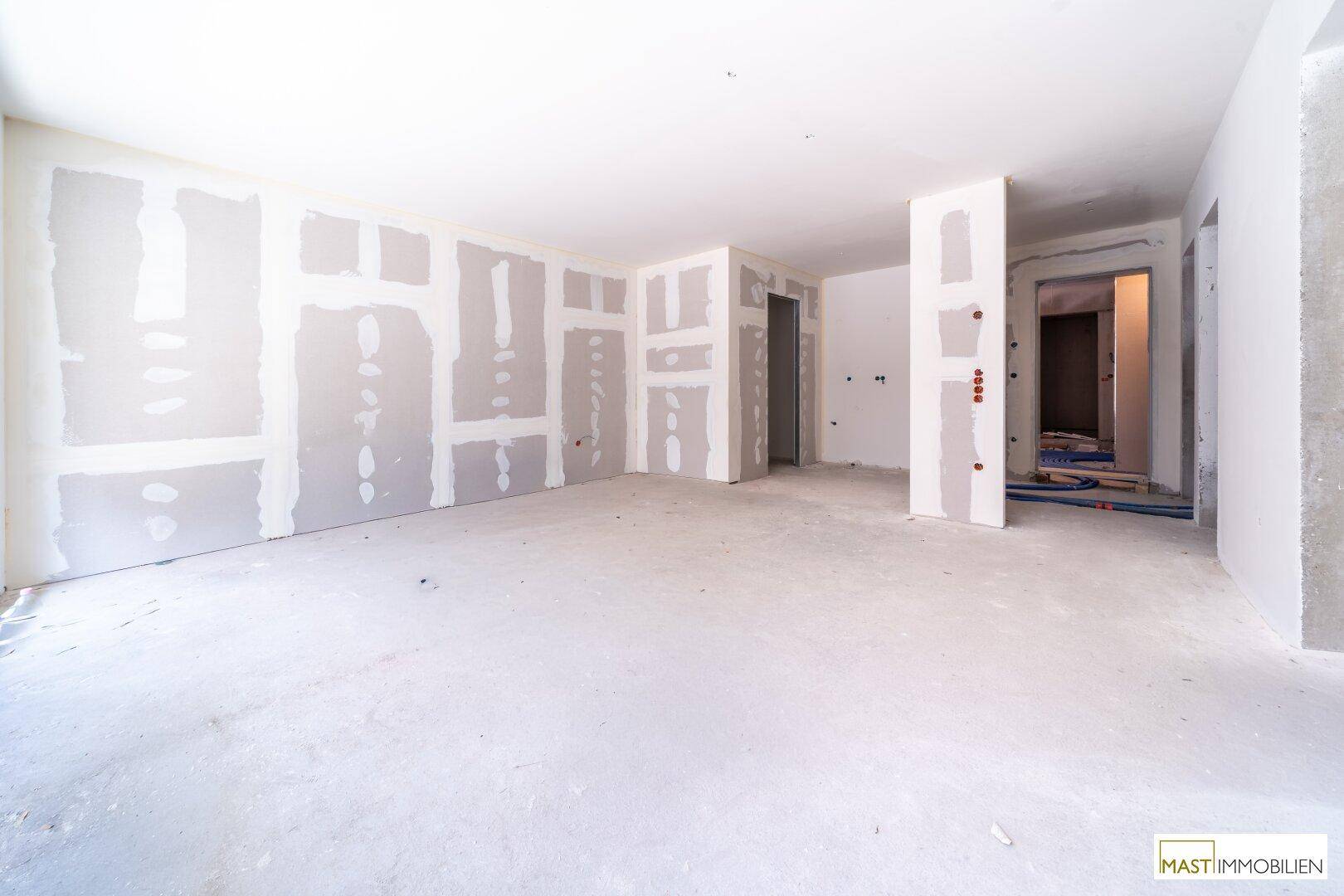 Rohbau-Innenraum mit Trockenbauwänden und Betonboden, bereit für den weiteren Ausbau.
