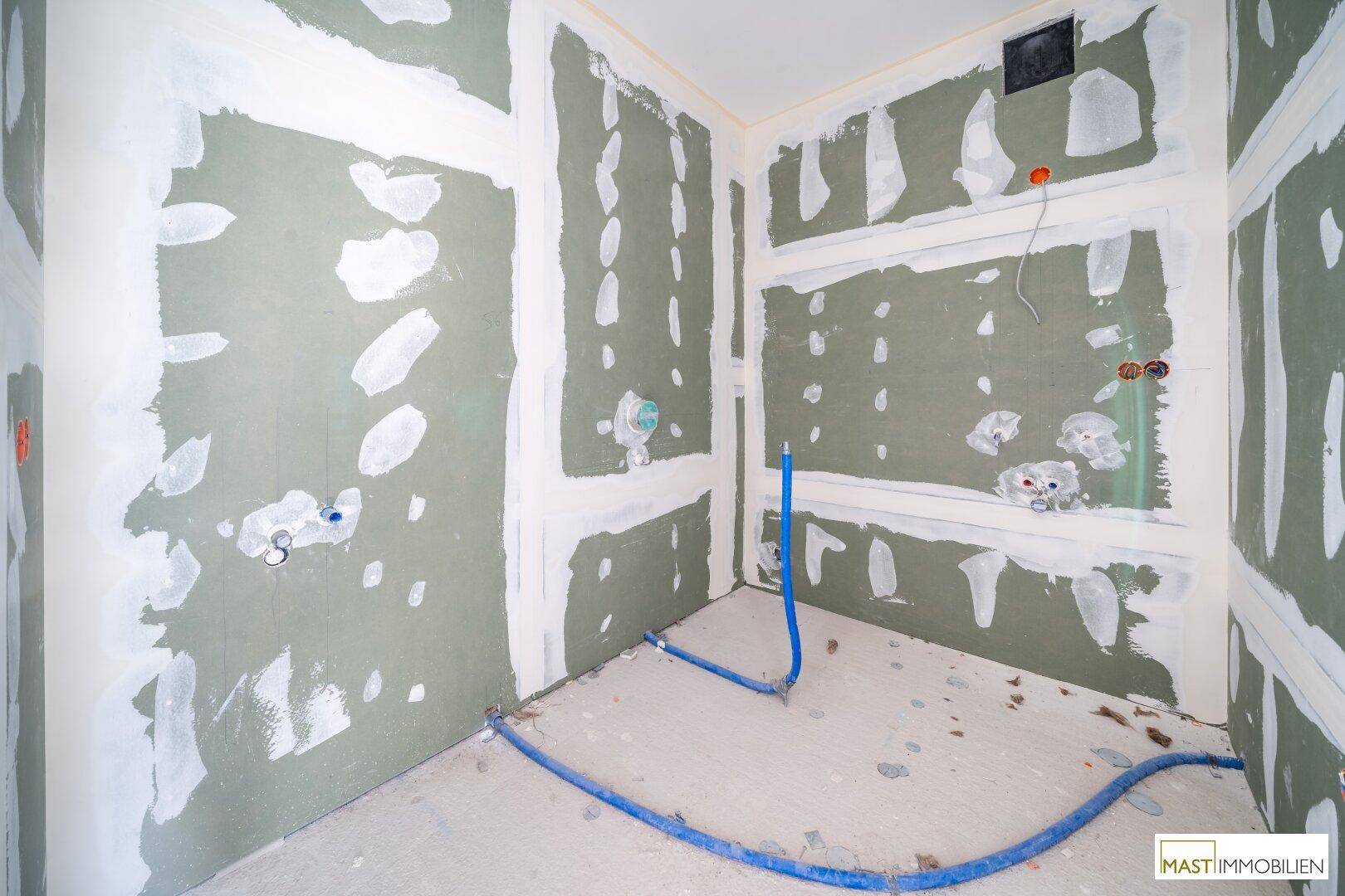 Rohbau eines Badezimmers mit vorbereiteten Anschlüssen für Sanitäranlagen und Trockenbauwänden.
