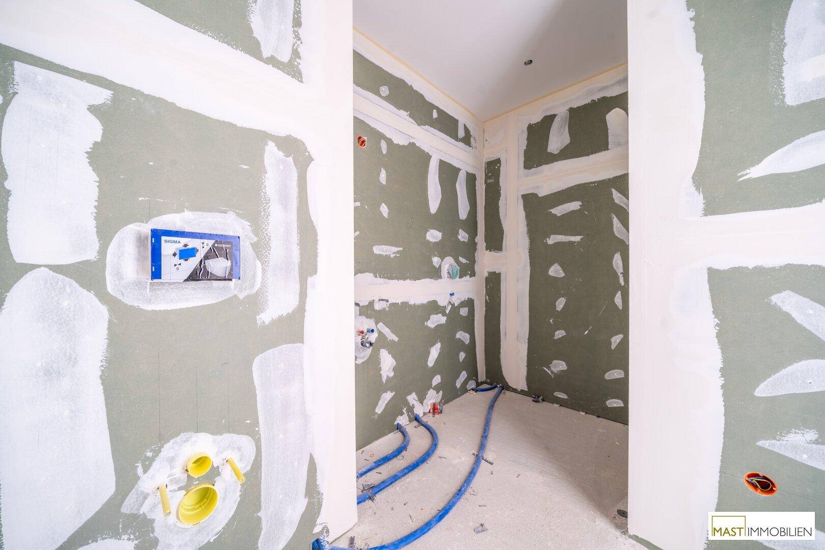 Rohbau eines Badezimmers mit grünen Trockenbauplatten und Sanitärvorinstallationen für WC und Waschbecken.