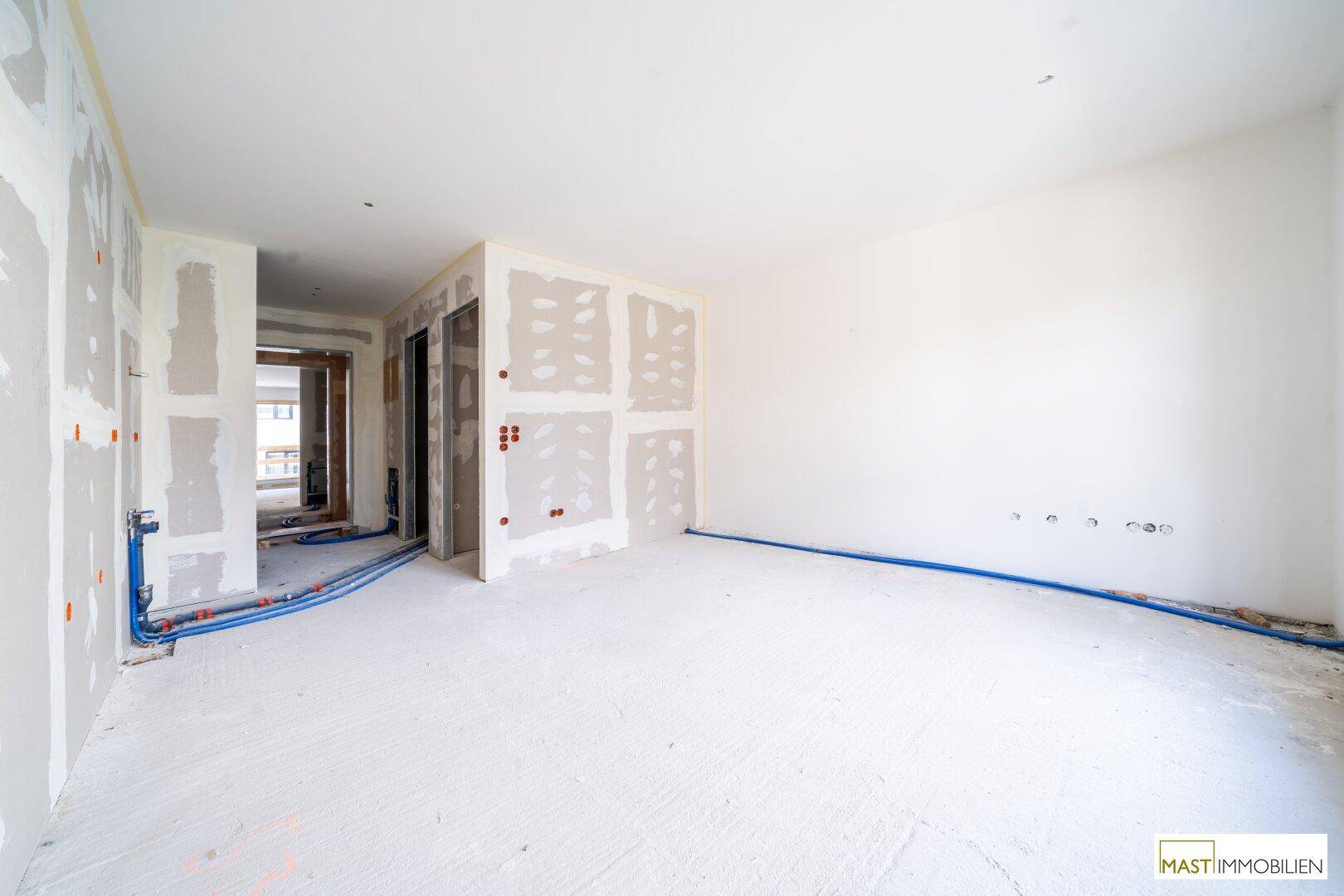 Unfertiger Innenraum mit Trockenbauwänden und sichtbaren Installationen, bereit für den weiteren Ausbau.