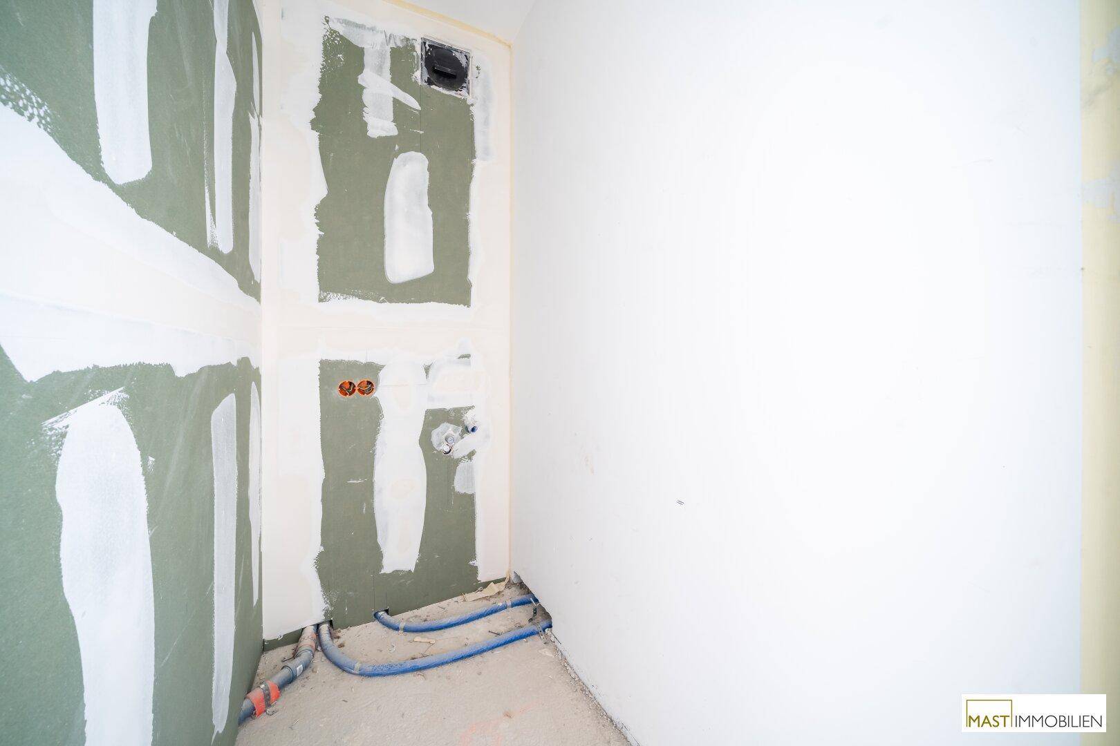 Unfertiges Badezimmer mit sichtbaren Rohrleitungen und Trockenbauwänden, bereit für die Fertigstellung.