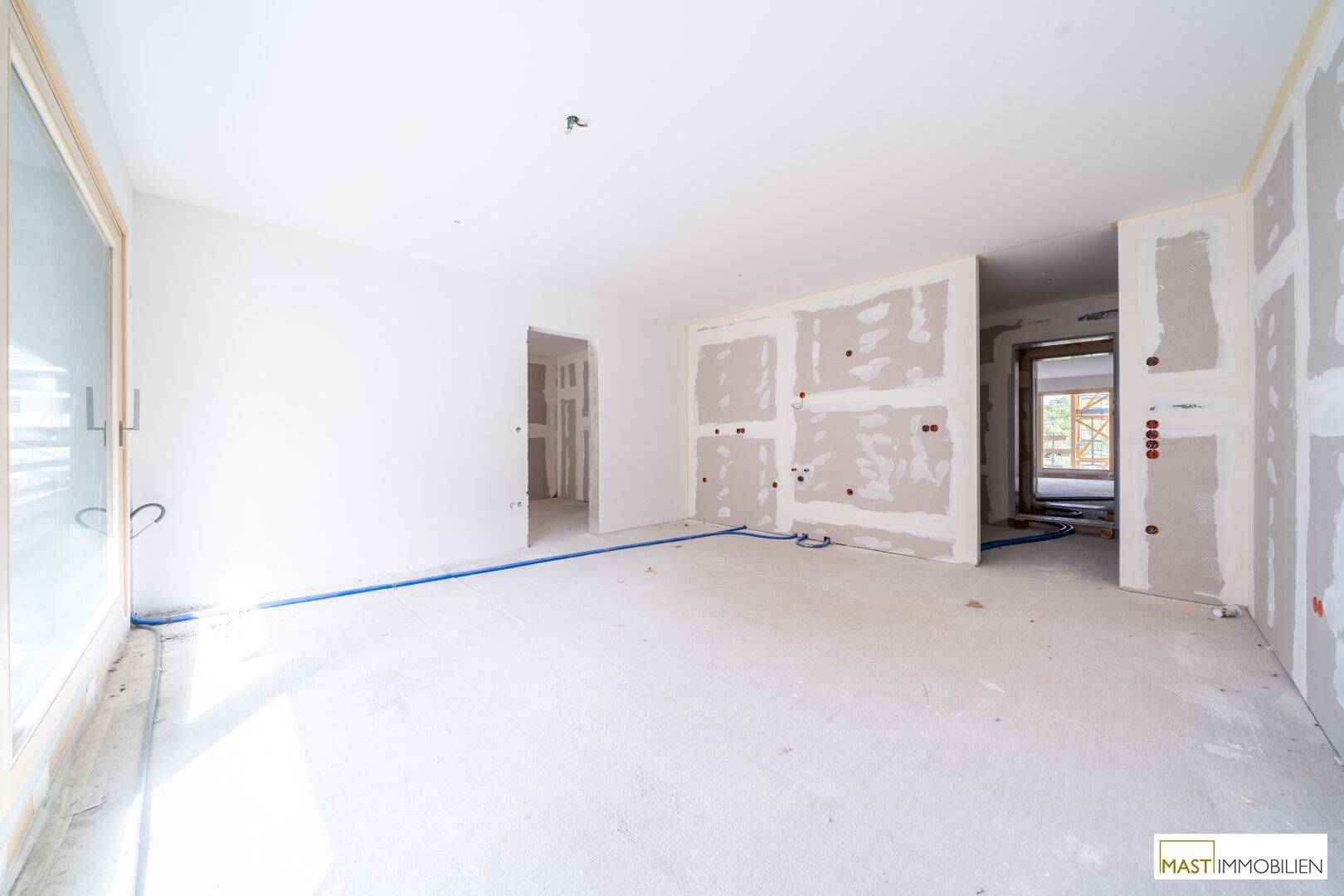 Innenraum im Rohbau mit Trockenbauwänden und sichtbaren Installationen für zukünftige Räume.