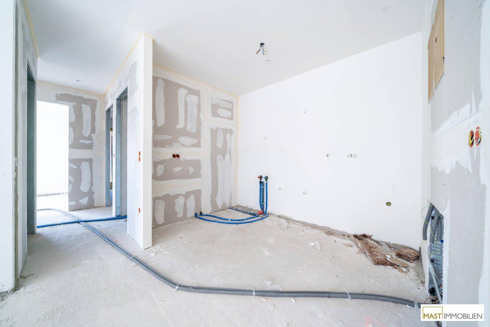 Rohbau-Innenraum mit sichtbaren Installationen und vorbereiteten Wänden für den weiteren Ausbau.
