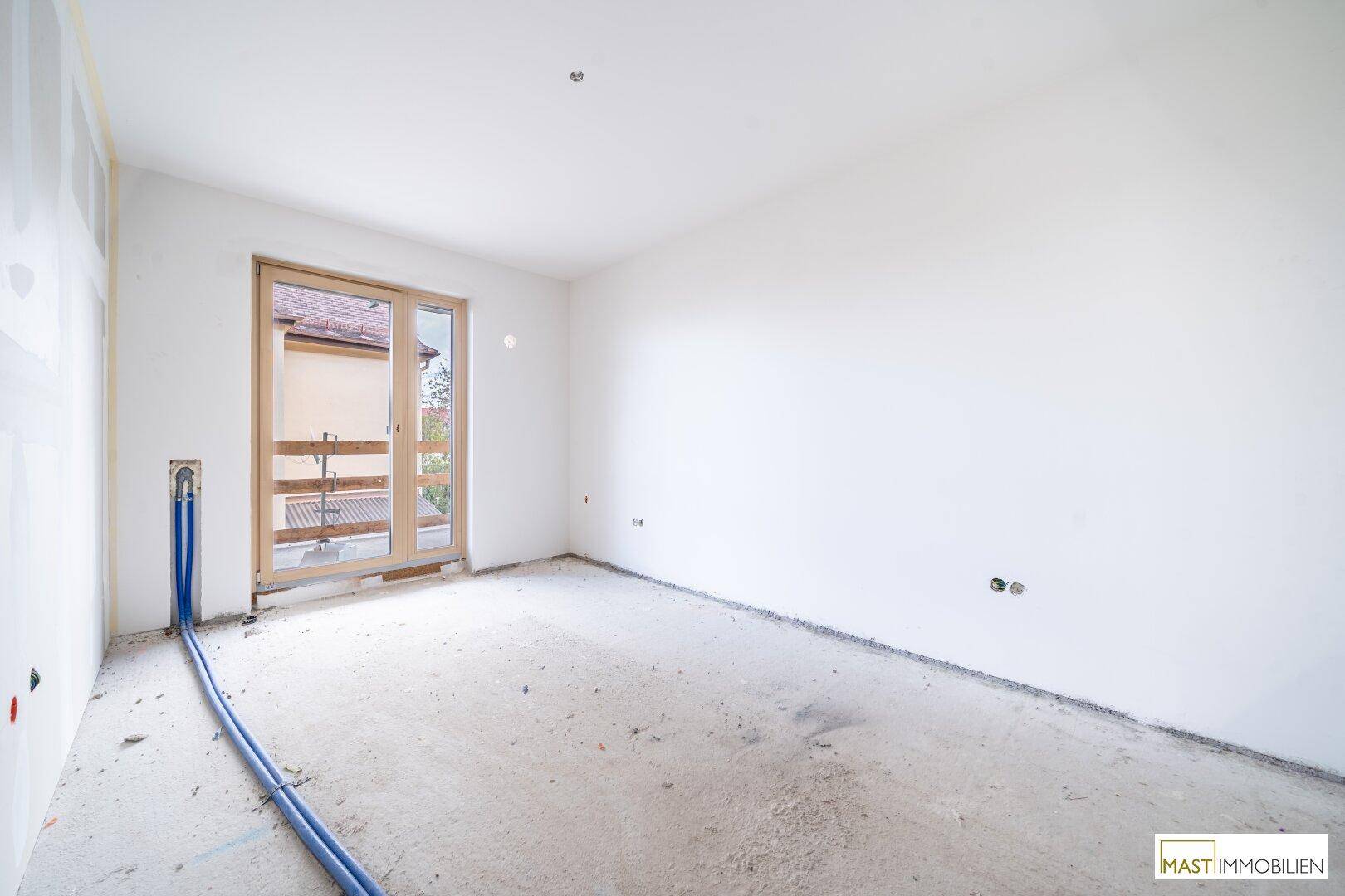 Unfertiges Schlafzimmer mit Zugang zu einem Balkon und Blick ins Grüne.