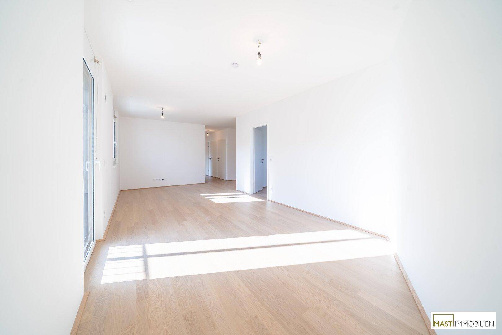 Geräumiges, helles Wohnzimmer mit Holzboden und viel Tageslicht, bereit zur individuellen Gestaltung.