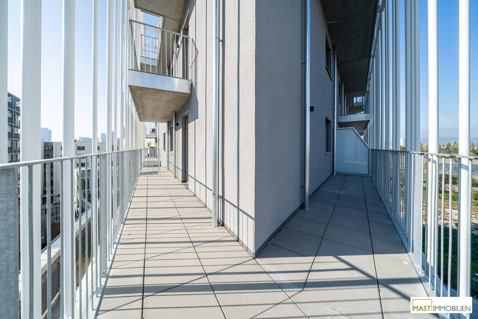 Breiter Balkon mit Fliesenboden und moderner Geländerkonstruktion, bietet viel Platz im Freien.