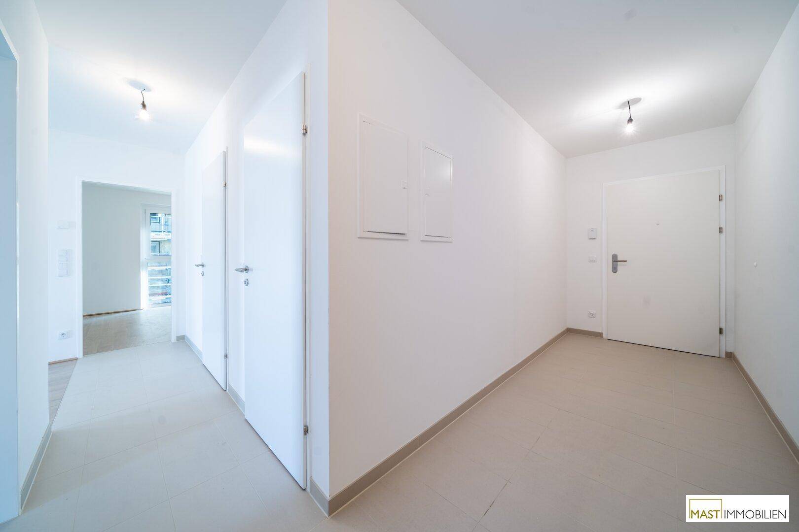 Heller Flur mit Fliesenboden und mehreren Türen, verbindet die verschiedenen Wohnbereiche der Wohnung.