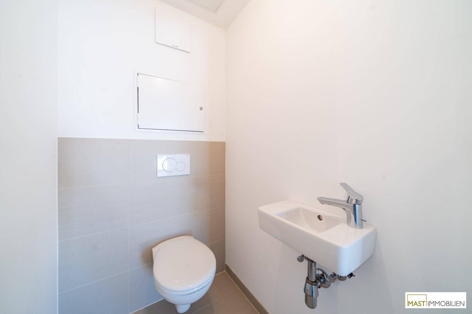Separates Gäste-WC mit wandhängender Toilette und kleinem Handwaschbecken, praktisch und modern.