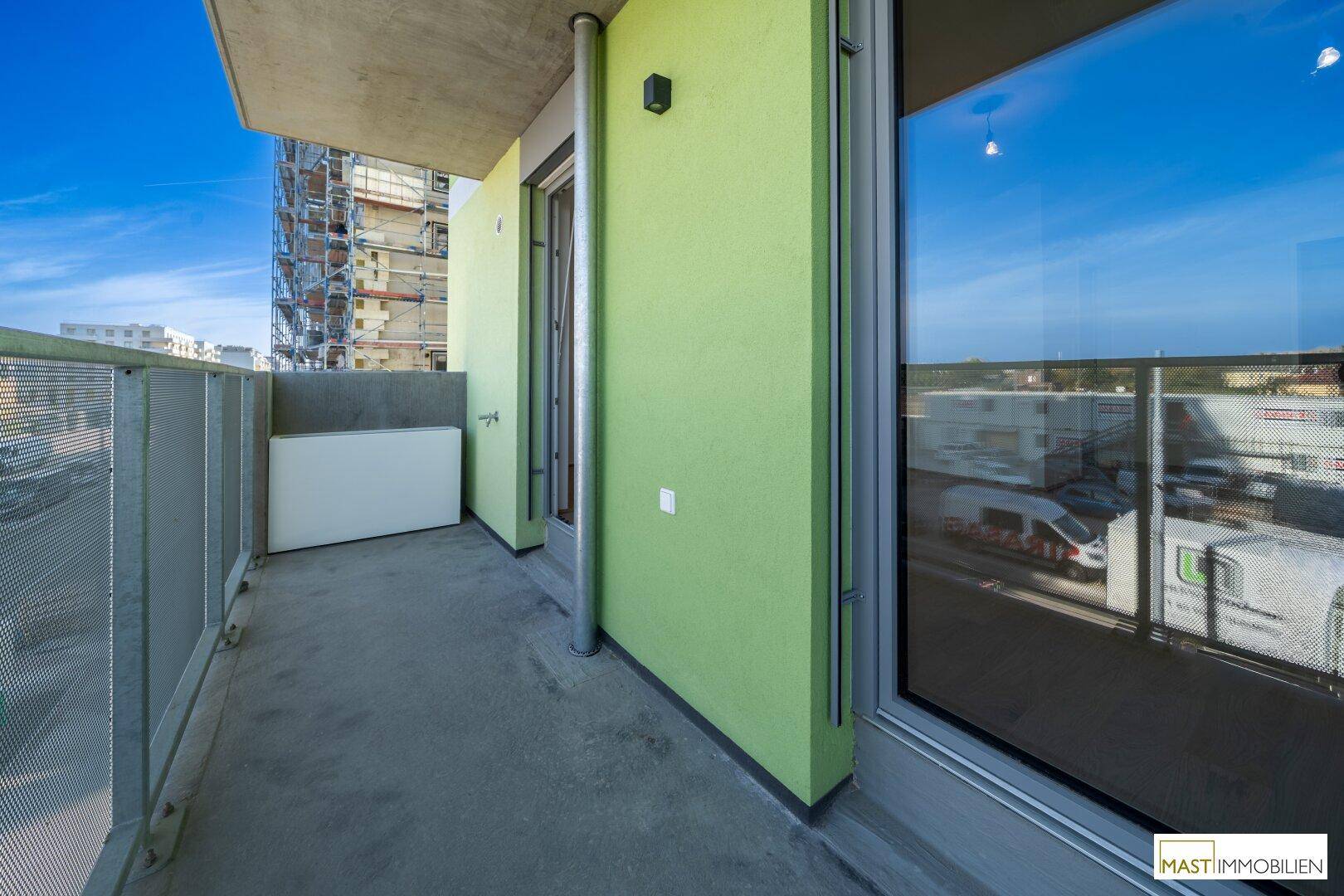 Langer Balkon mit grün gestrichener Fassade und Zugang zum Innenbereich, bietet frische Luft.
