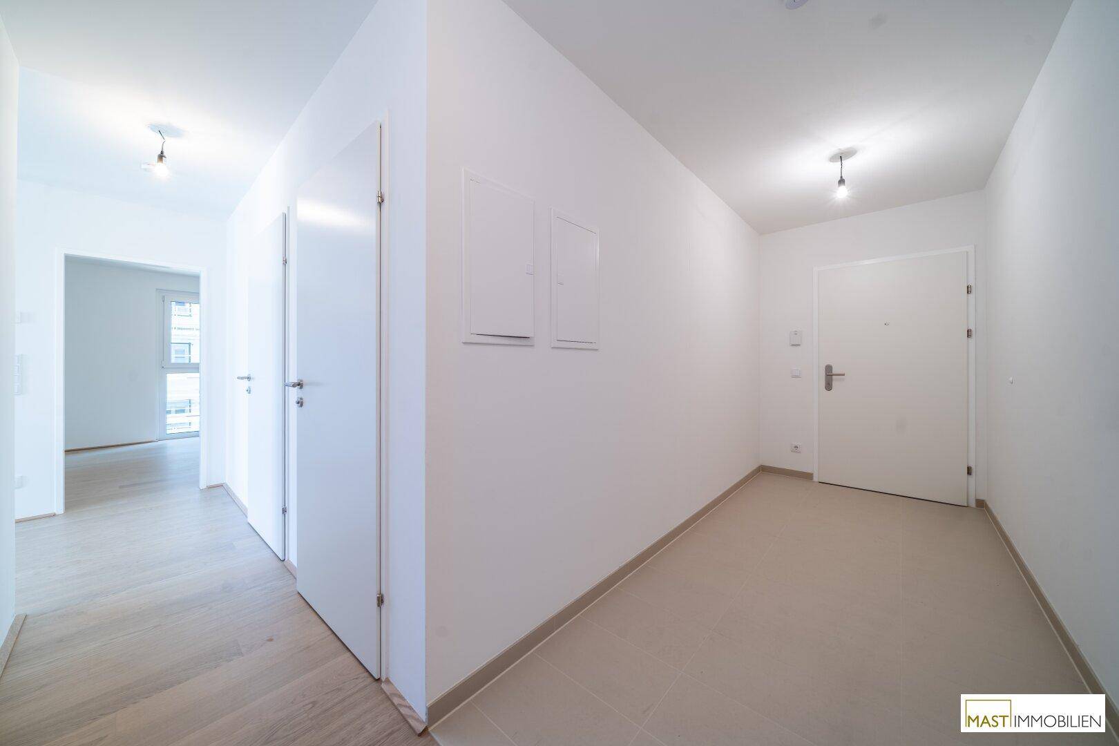 Heller Eingangsbereich mit Fliesenboden und Zugang zu weiteren Räumen, modern und funktional.
