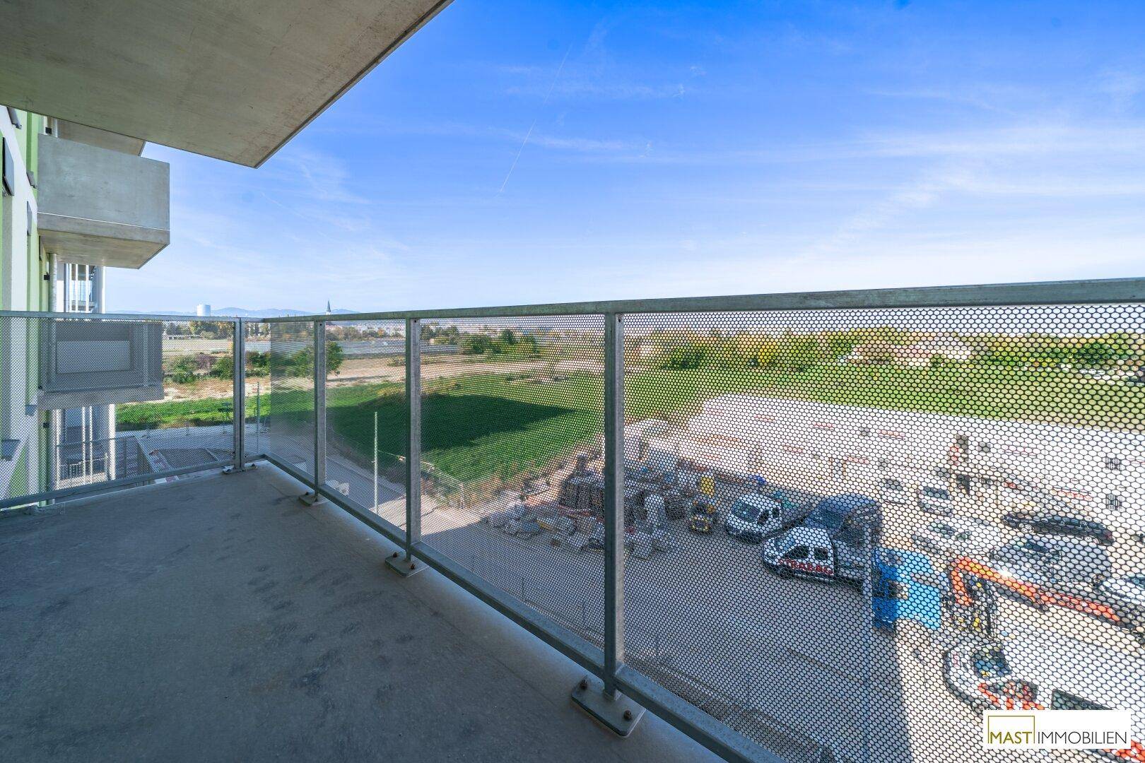 Geräumiger Balkon mit Metallgeländer und weitem Blick über die Umgebung und Landschaft.