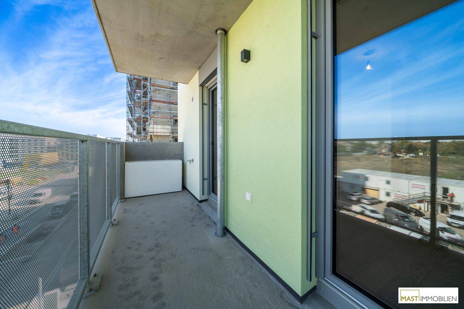 Heller Balkon mit grün gestrichener Wand und Blick auf die umliegende Bebauung und Landschaft.