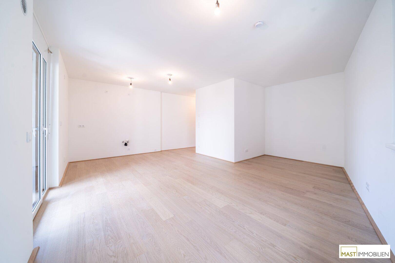 Geräumiges, unmöbliertes Wohnzimmer mit hellen Wänden und Holzboden, bereit zur individuellen Gestaltung.