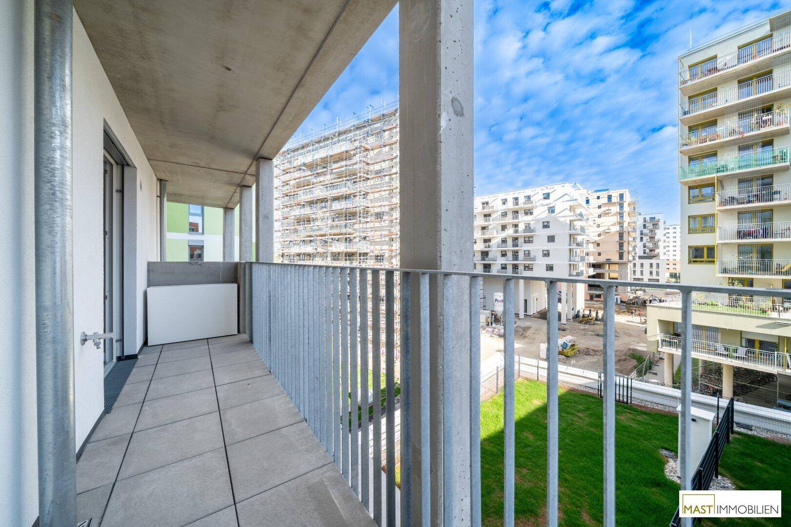 Langer Balkon mit Fliesenboden und Metallgeländer, bietet einen Blick auf die grüne Umgebung.