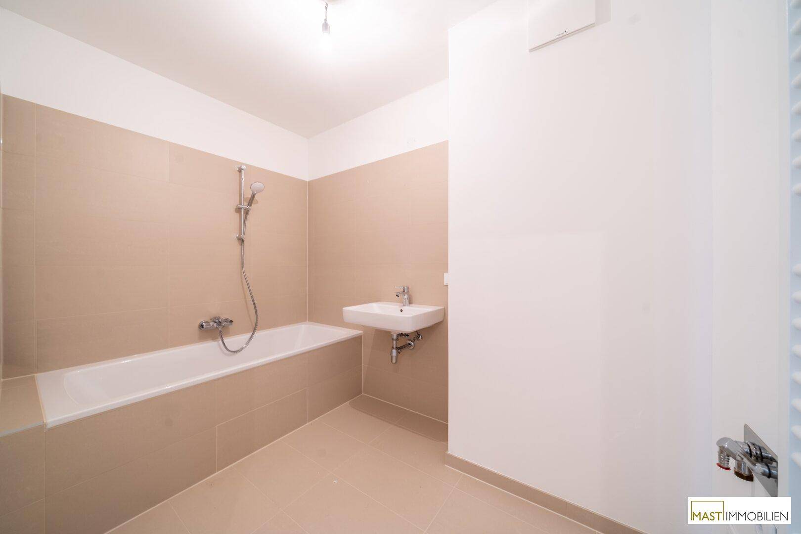Modernes Badezimmer mit Badewanne, Duscharmatur und kleinem Waschbecken.