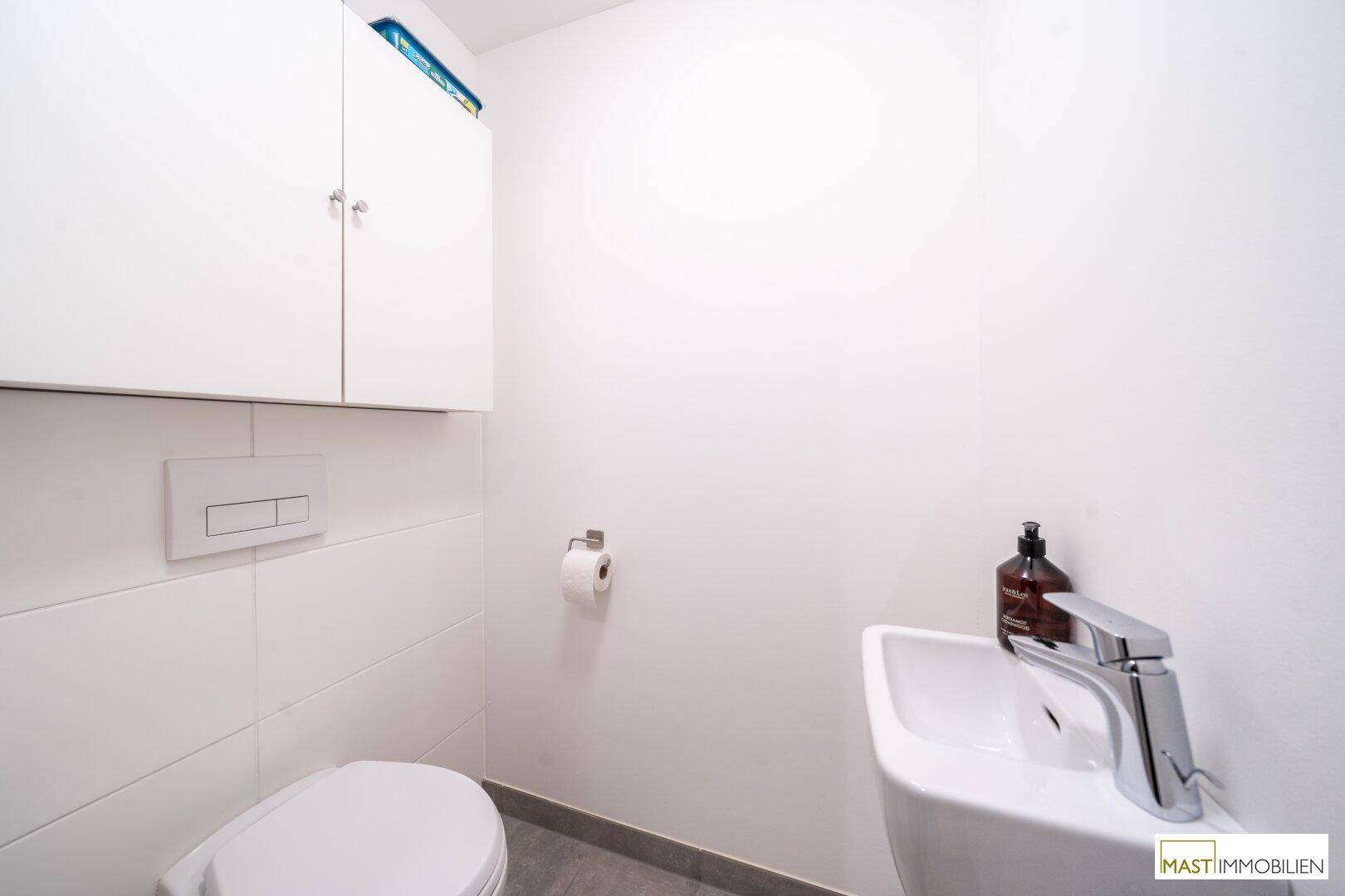 Separates Gäste-WC mit wandhängender Toilette und kleinem Waschbecken.