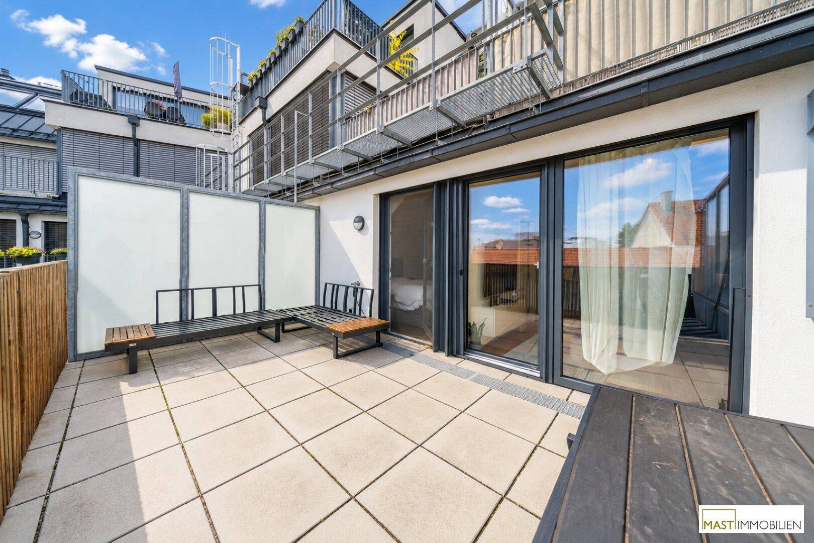 Große Terrasse mit Zugang zu den Innenräumen und Blick auf die Nachbargebäude.