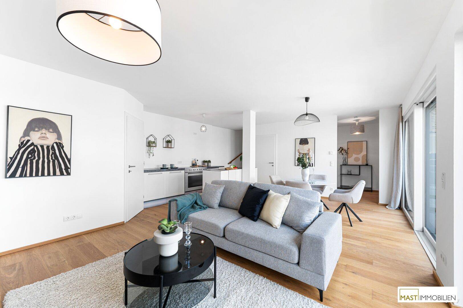 Heller, offener Wohnbereich mit Sofa, Couchtisch und Blick auf den Essbereich und die Küche.