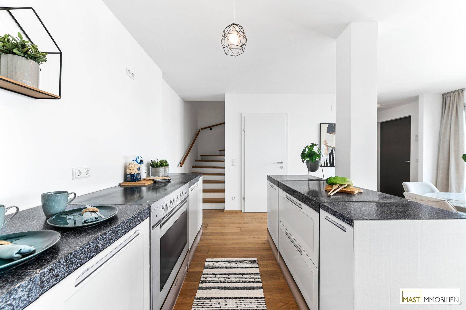 Helle, moderne Küche mit viel Arbeitsfläche, weißen Fronten und Holzboden.