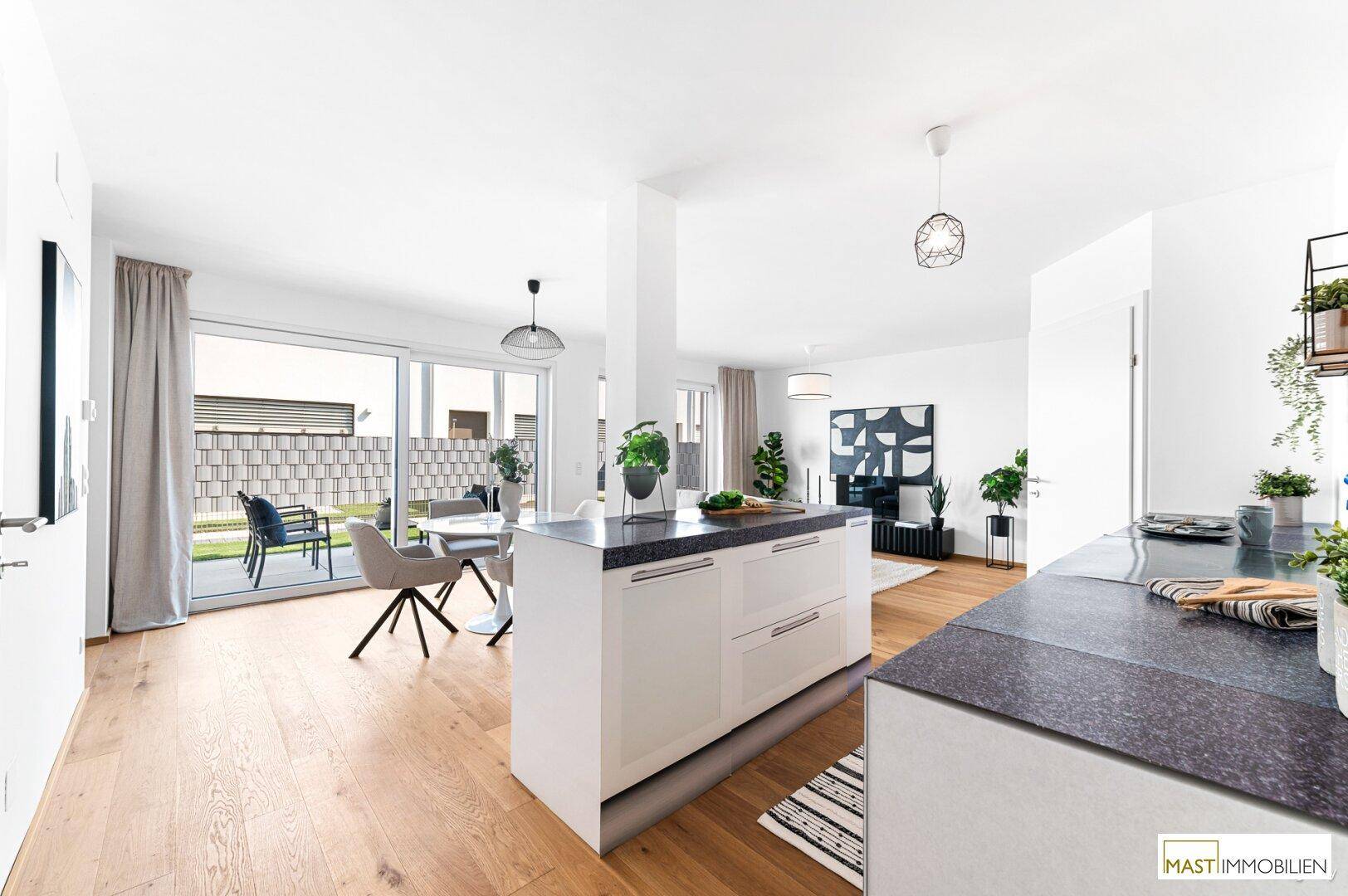 Geräumige Küche mit Kochinsel und offener Verbindung zum Ess- und Wohnbereich mit Terrassenzugang.