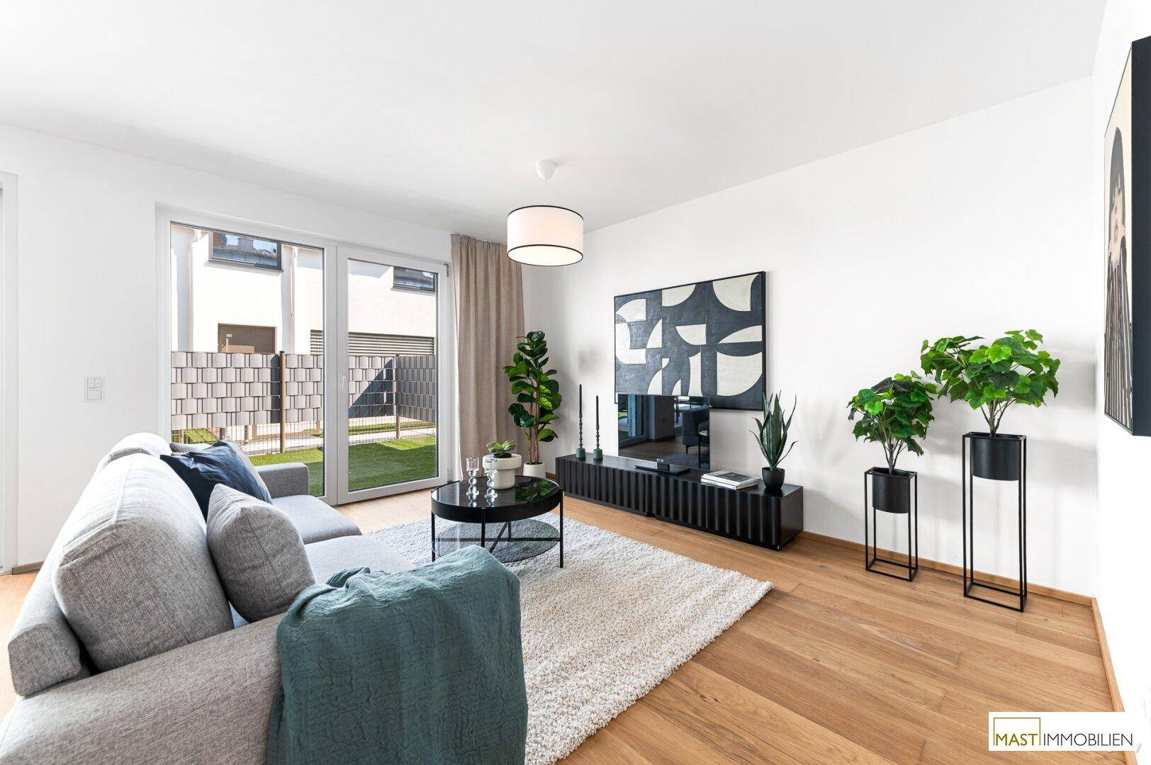 Gemütliches Wohnzimmer mit Sofa, Fernseher und dekorativen Pflanzen, hell und modern eingerichtet.