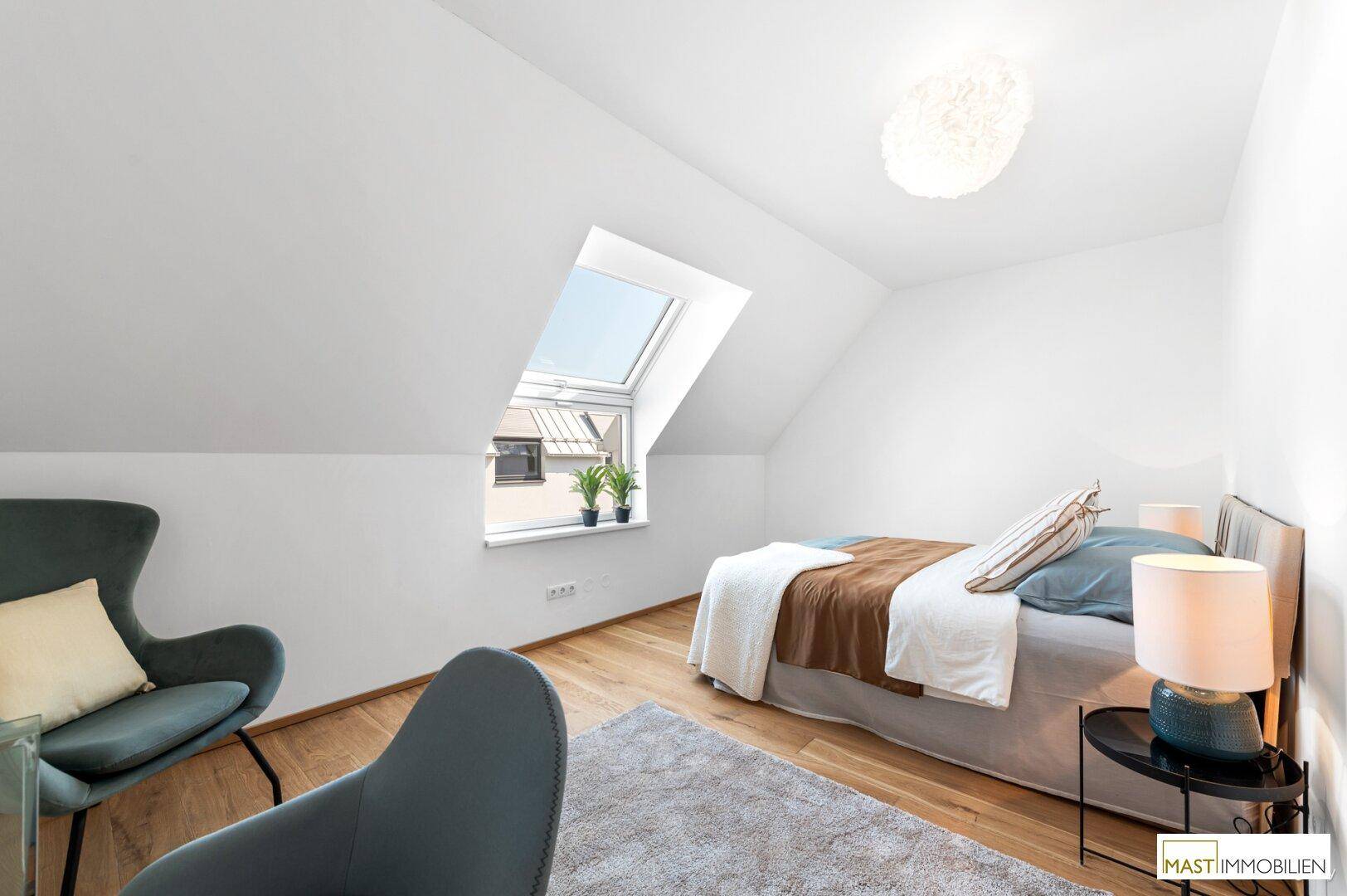 Komfortables Schlafzimmer im Dachgeschoss mit Bett, Lesesessel und Dachfenster für viel Licht.