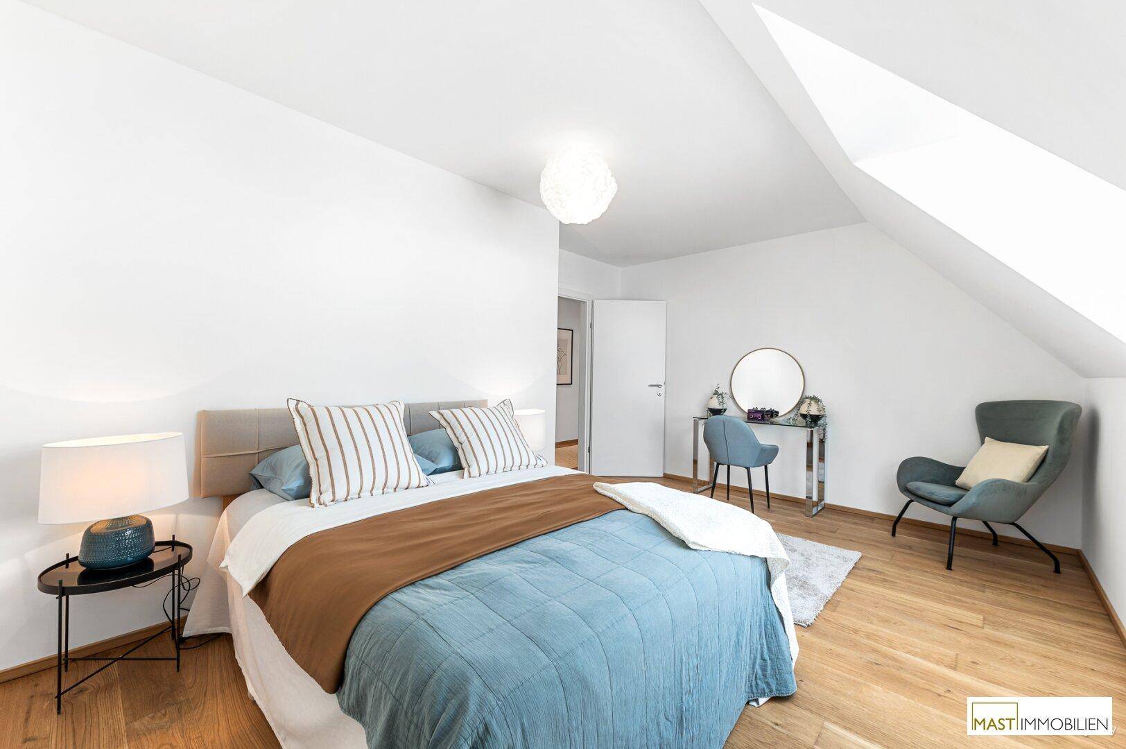 Stilvolles Schlafzimmer mit Doppelbett, Schminktisch und gemütlichem Sessel im Dachgeschoss.