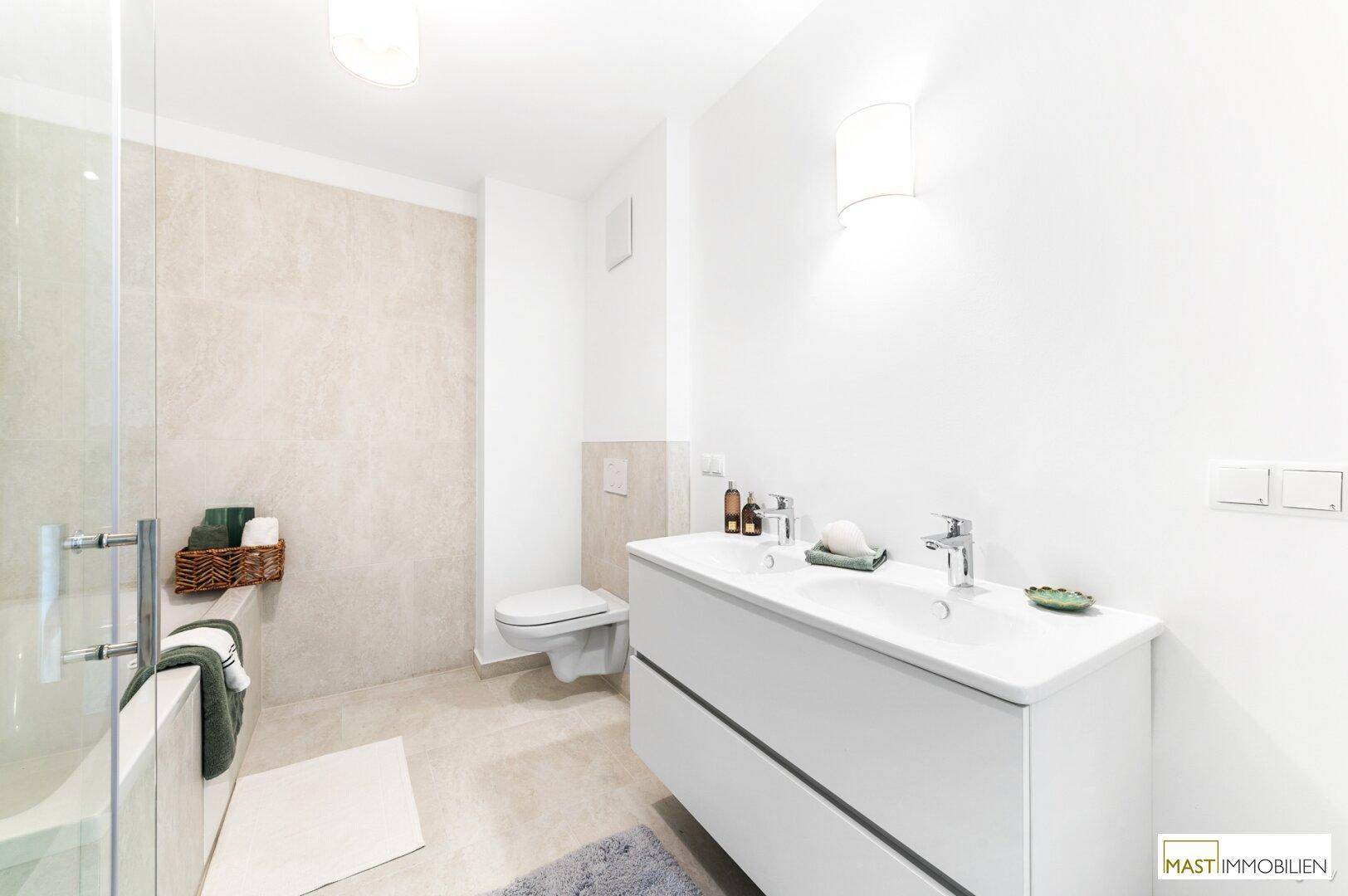 Helles Badezimmer mit Doppelwaschbecken, großem Spiegel und modernen Fliesen an den Wänden.