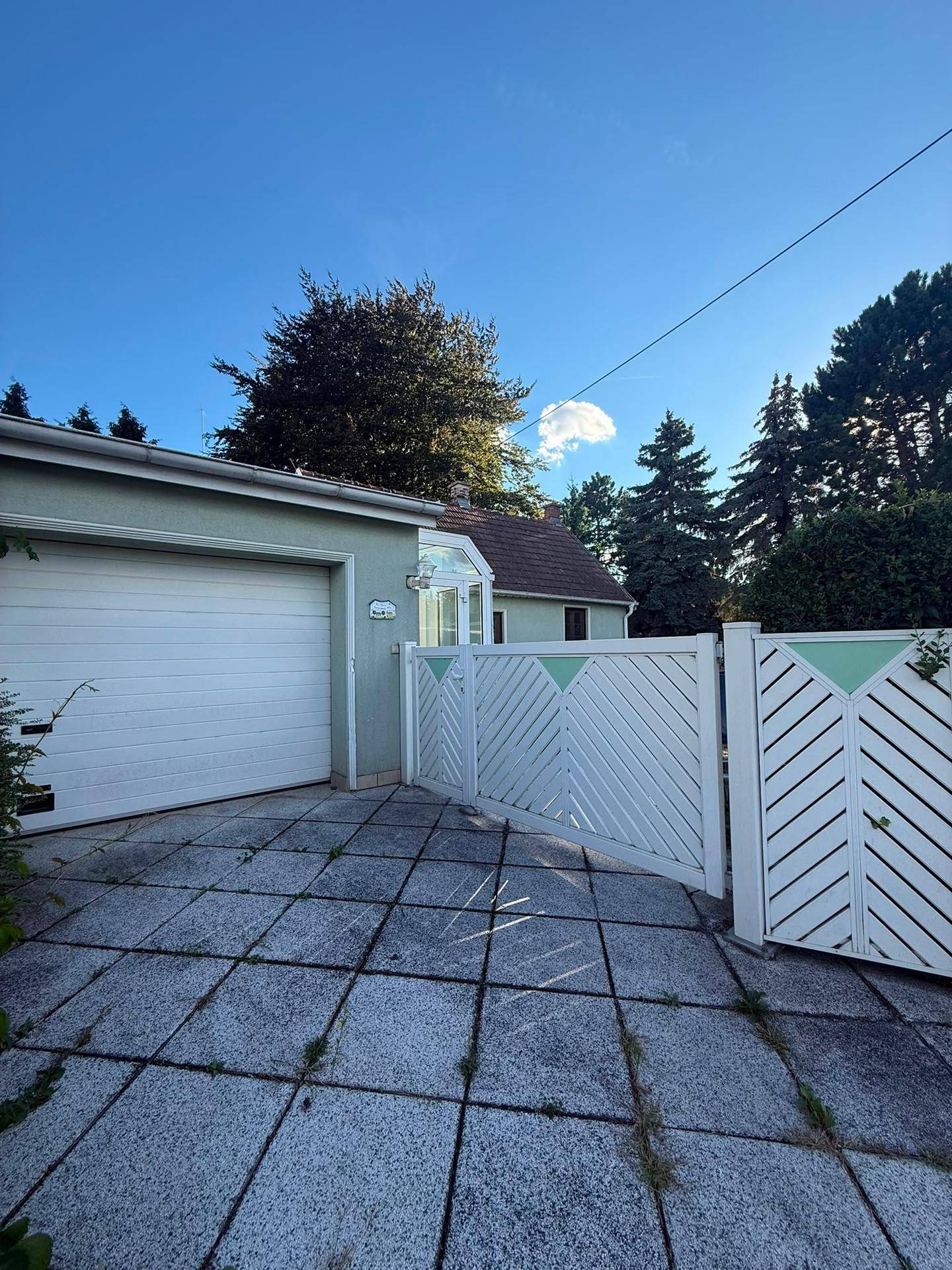 Einfahrt mit Garage, weißem Tor und gepflastertem Bereich vor dem Haus.