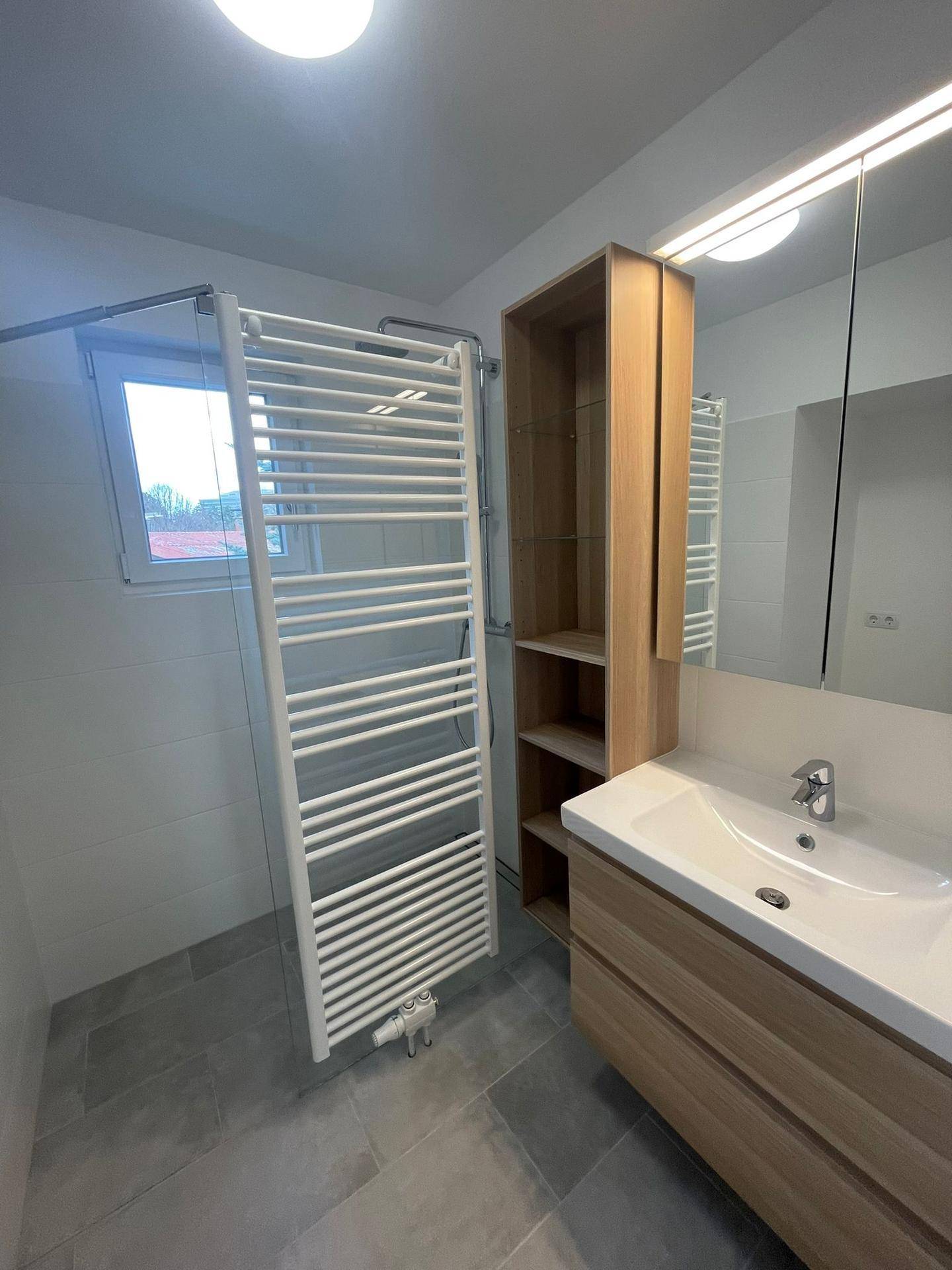 Modernes Badezimmer mit Einzelwaschbecken, Spiegelschrank und beheiztem Handtuchhalter.
