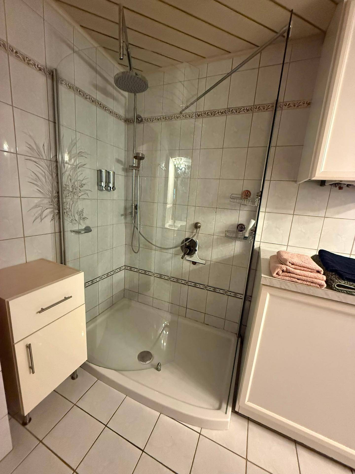 Badezimmer mit Duschkabine, Regendusche und hellen Fliesen.