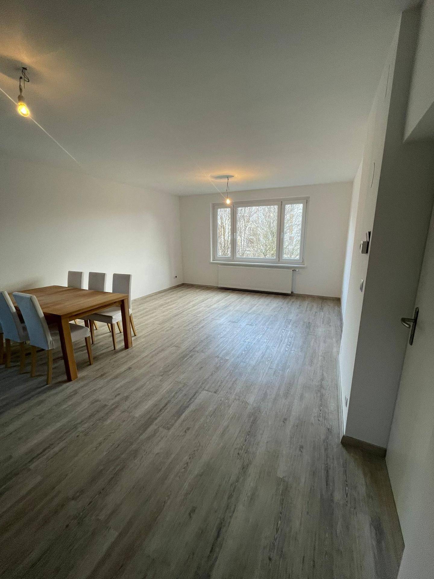 Heller Wohn-Essbereich mit modernem Laminatboden und einem Esstisch für mehrere Personen.
