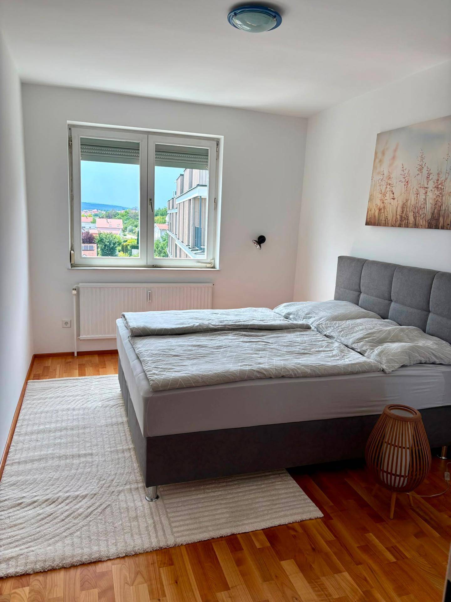 Schlafzimmer mit Doppelbett, Holzboden und Fenster mit Blick auf die umliegende Landschaft.