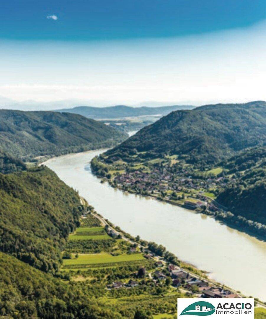 Malerische Luftaufnahme eines Flusstals mit grünen Hügeln und kleinen Siedlungen.