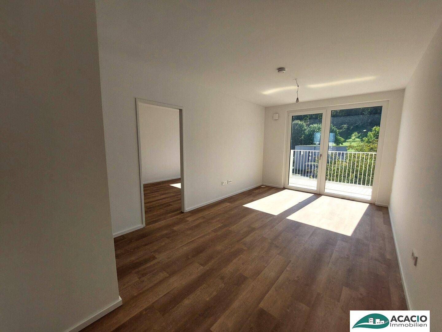 Lichtdurchfluteter Wohnbereich mit Laminatboden und großem Fenster zum Balkon.