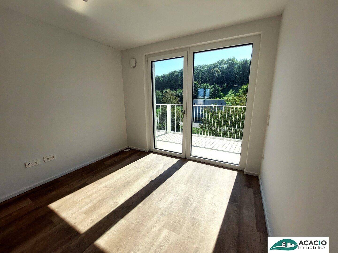 Helles Schlafzimmer mit Laminatboden und direktem Zugang zum sonnigen Balkon.
