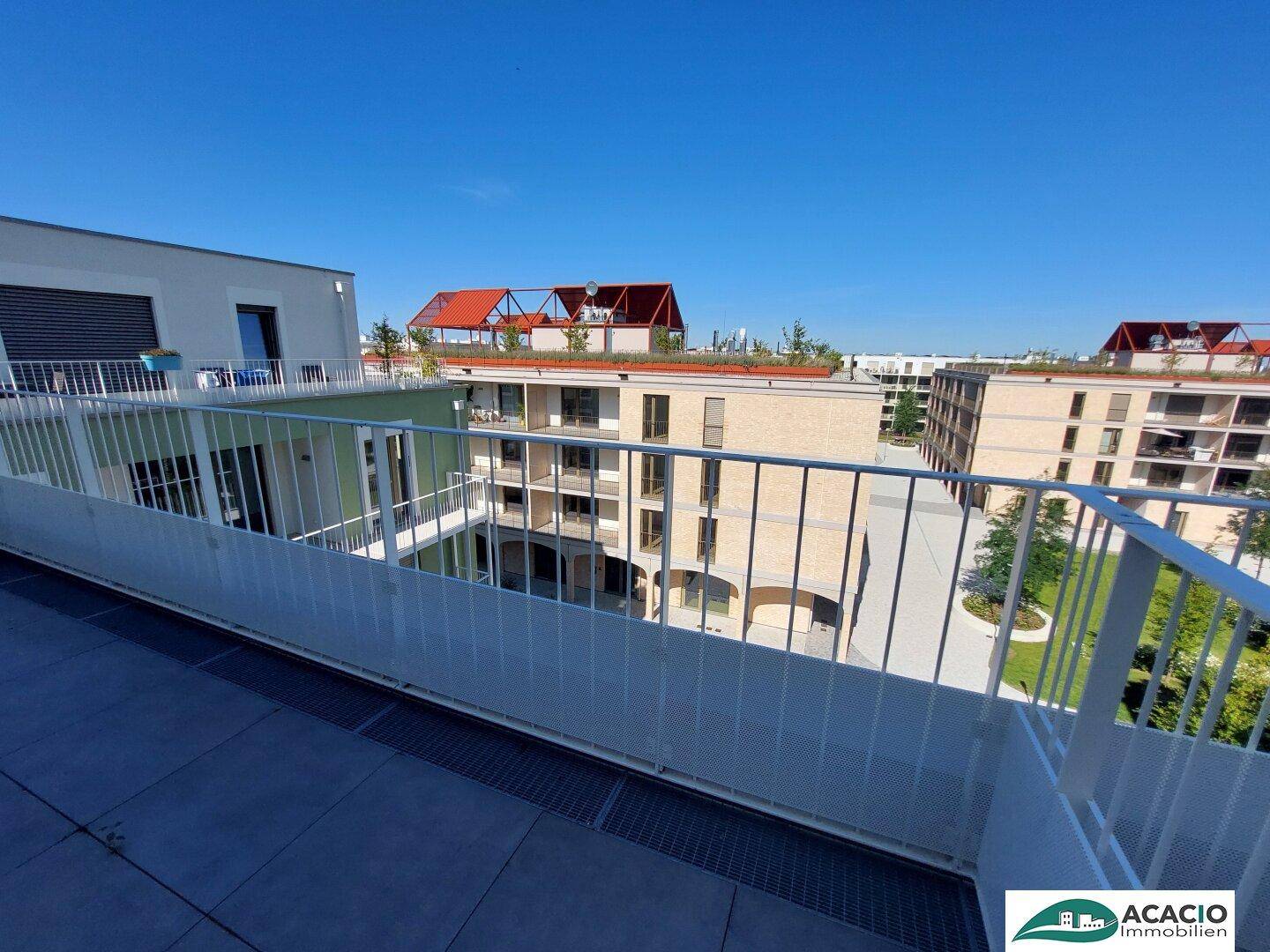 Große Dachterrasse mit Fliesenboden und weitem Blick über eine moderne Wohnanlage.