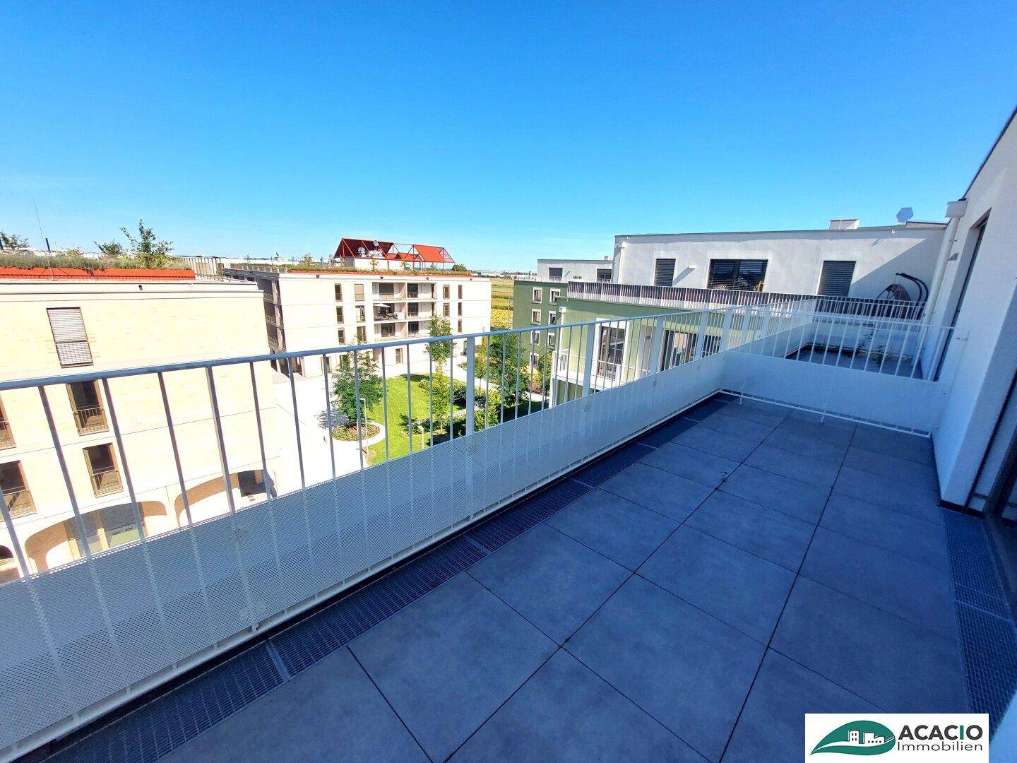 Weitläufige Terrasse mit Blick auf die begrünten Innenhöfe der modernen Wohnanlage.