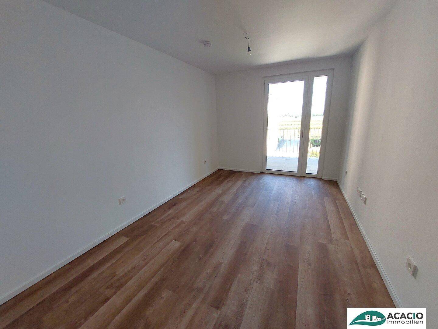 Helles Schlafzimmer mit Laminatboden und direktem Zugang zu einem Außenbereich.