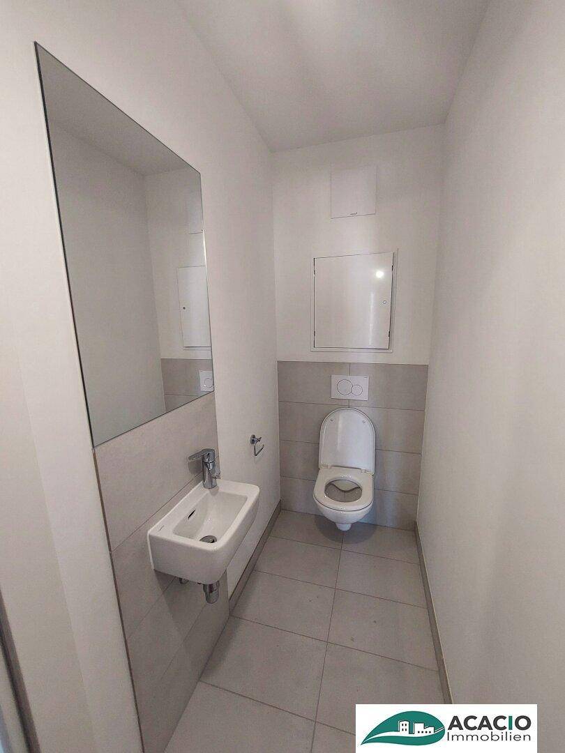 Modernes Gäste-WC mit wandhängender Toilette und kleinem Waschbecken.